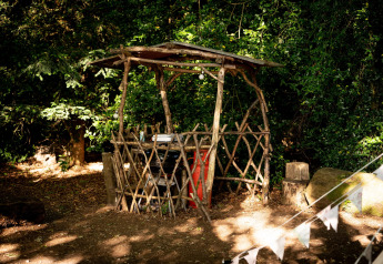 Capanno rustico di legno naturale con tetto semplice, immerso nei boschi vicino alla Moroccan Bell Tent, UK.