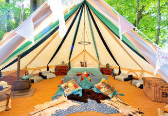 Vista interna della Moroccan Bell Tent nel Regno Unito con cuscini colorati, tappeti e mobili in legno.