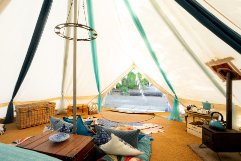 Interno della Moroccan Bell Tent nel Regno Unito con cuscini colorati, bauli e set da tè caratteristico.