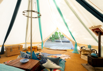 Interno della Moroccan Bell Tent nel Regno Unito con cuscini colorati, bauli e set da tè caratteristico.