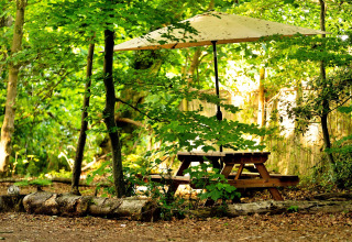 Tavolo da picnic con ombrellone sotto alberi verdi al Moroccan Bell Tent nel Regno Unito.