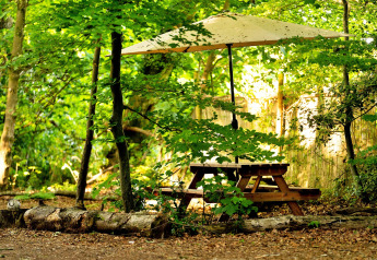 Tavolo da picnic con ombrellone sotto alberi verdi al Moroccan Bell Tent nel Regno Unito.