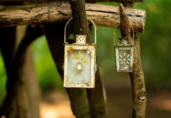 Due lanterne decorative appese ai rami vicino alla Moroccan Bell Tent nel Regno Unito.