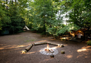 Tenda Moroccan Bell Tent in campeggio con falò, tipi e bosco nel Regno Unito, luce filtrata dagli alberi.