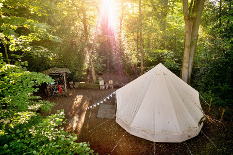La luce del sole illumina la Moroccan Bell Tent in un tranquillo campeggio nel bosco nel Regno Unito.