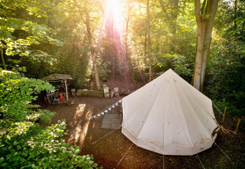 La luce del sole illumina la Moroccan Bell Tent in un tranquillo campeggio nel bosco nel Regno Unito.