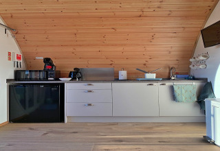 Moderne pod-keuken in Hundle Dale, Verenigd Koninkrijk, met houten plafond en compacte toestellen.