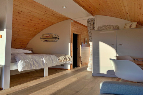 Modern houten interieur in de 'Hundle Dale' pod in het VK, met bed, kast en veel zonlicht.
