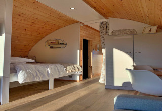 Modern houten interieur in de 'Hundle Dale' pod in het VK, met bed, kast en veel zonlicht.