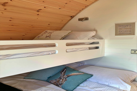 Binnenzicht van de slaapruimte in de 'Hundle Dale' pod in het VK met stapelbedden en dierenkussens.
