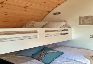 Binnenzicht van de slaapruimte in de 'Hundle Dale' pod in het VK met stapelbedden en dierenkussens.
