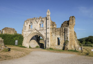 Oude ruïnes van een historisch gebouw in Hundle Dale, VK, met stenen boog en zonnige blauwe lucht.