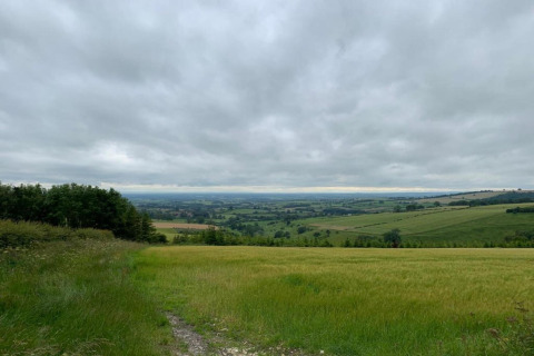 Vue sur la campagne et des champs verts prise depuis un pod, sous un ciel nuageux et un paysage vallonné.