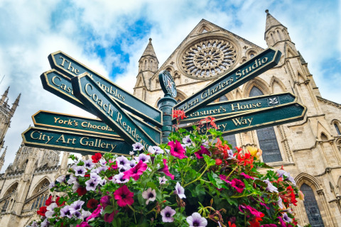 Kleurrijke bloemen en richtingborden voor een indrukwekkende gotische kathedraal in York, Engeland.
