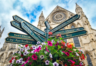 Kleurrijke bloemen en richtingborden voor een indrukwekkende gotische kathedraal in York, Engeland.