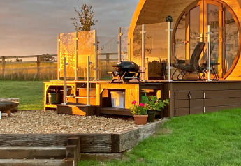 Zonnige Hundle Dale pod in het Verenigd Koninkrijk met houten terras, glazen balustrade en barbecue.