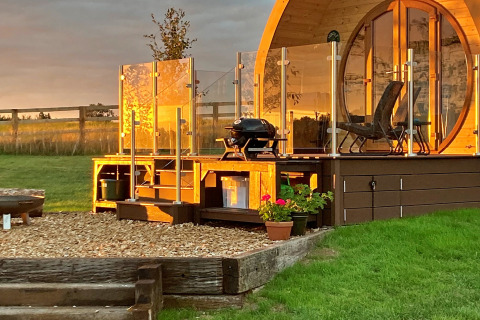 Zonnige Hundle Dale pod in het Verenigd Koninkrijk met houten terras, glazen balustrade en barbecue.
