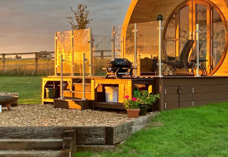 Zonnige Hundle Dale pod in het Verenigd Koninkrijk met houten terras, glazen balustrade en barbecue.
