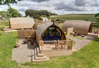 Pods de glamping en bois à Blackcleugh Glamping, Royaume-Uni, entourés de verdure et de campagne.