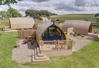 Houten glamping pods bij Blackcleugh Glamping in het Verenigd Koninkrijk, midden in het groene landschap.