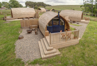 Houten glampingpods met grindpaden en terrassen bij Blackcleugh Glamping in het Britse platteland.