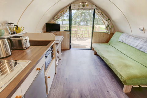 Interieur van de Blackcleugh Glamping pod in het Verenigd Koninkrijk met keuken, groene bank en terras.