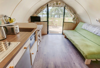 Interieur van de Blackcleugh Glamping pod in het Verenigd Koninkrijk met keuken, groene bank en terras.
