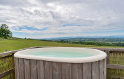 Außenwhirlpool mit Blick auf grüne Felder bei Bramble Yurt im Vereinigten Königreich unter bewölktem Himmel