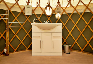Moderne hvidt badeværelsesskab med vask i en traditionel Bramble Yurt i Storbritannien.