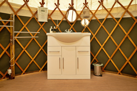 Mobile lavabo moderno bianco all'interno di una tradizionale Bramble Yurt nel Regno Unito.