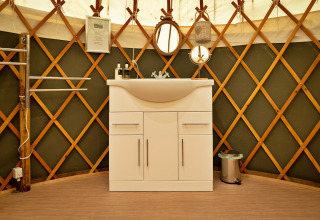 Mobile lavabo moderno bianco all'interno di una tradizionale Bramble Yurt nel Regno Unito.