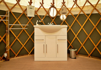 Moderne witte wastafelmeubel in een traditionele Bramble Yurt in het Verenigd Koninkrijk.