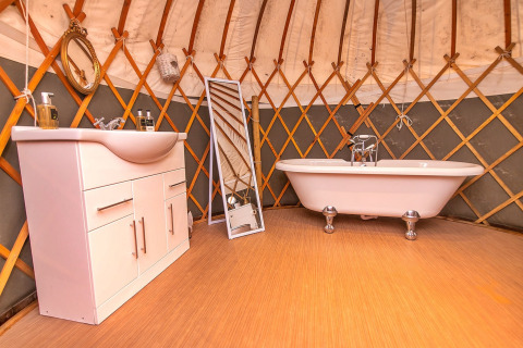 Bagno all'interno del Bramble Yurt nel Regno Unito, con vasca, lavandino e uno specchio intero.