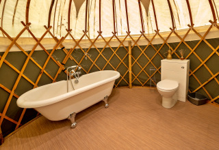 Luksuriøst badeværelse i Bramble Yurt med fritstående badekar og toilet, placeret i Storbritannien.