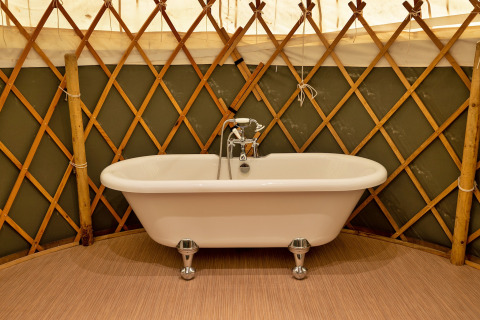 Vasca da bagno indipendente all'interno di Bramble Yurt nel Regno Unito, circondata da una struttura in legno.
