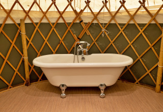 Vasca da bagno indipendente all'interno di Bramble Yurt nel Regno Unito, circondata da una struttura in legno.