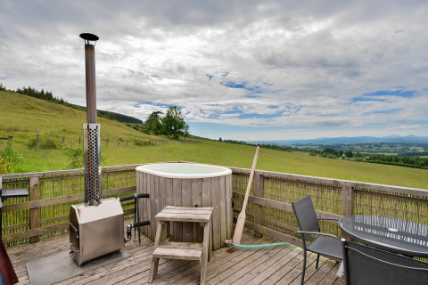 Terrazza esterna alla Bramble Yurt nel Regno Unito con vasca idromassaggio e vista sulle verdi colline.