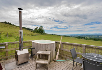 Buiten terras bij Bramble Yurt in het Verenigd Koninkrijk met hottub en prachtig uitzicht op groene velden.