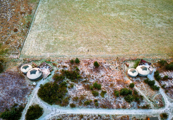 Aerial view of Bramble Yurt in the UK, featuring two round tents with decks in a frosty natural setting.