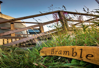 Photo of Bramble Yurt in the UK, featuring a wooden sign and outdoor steps leading up to the yurt entrance.