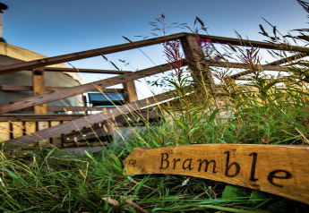 Foto von Bramble Yurt in Großbritannien mit Holzschild im Vordergrund und der Yurt im Hintergrund.