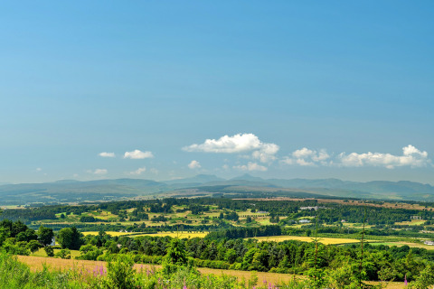 Scenic view from Bramble Yurt in the UK showing lush fields, rolling hills, and a bright blue sky.