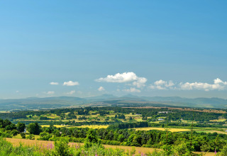 Scenic view from Bramble Yurt in the UK showing lush fields, rolling hills, and a bright blue sky.