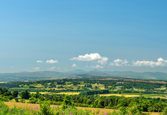 Landschaftsblick von Bramble Yurt in Großbritannien mit grünen Feldern, Bäumen und blauem Himmel.