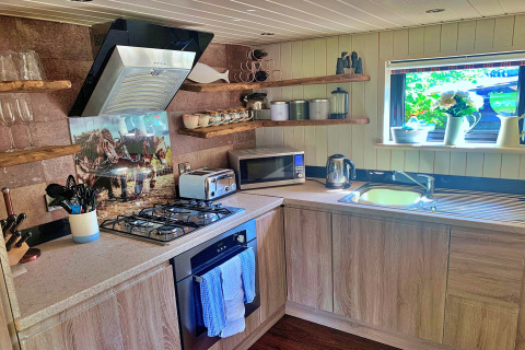Cuisine moderne au Oak Tree Lodge, Royaume-Uni, avec placards en bois et étagères ouvertes sous une fenêtre.