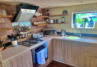 Cuisine moderne au Oak Tree Lodge, Royaume-Uni, avec placards en bois et étagères ouvertes sous une fenêtre.
