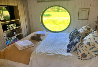 Chambre d’Oak Tree Lodge au Royaume-Uni, grande fenêtre ronde, lit double, coussins à motifs animaliers.