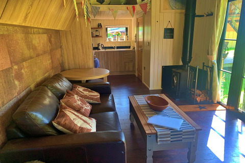 Séjour chaleureux à Oak Tree Lodge, maison mobile au Royaume-Uni avec canapé, poêle et coin cuisine.