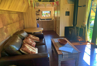 Séjour chaleureux à Oak Tree Lodge, maison mobile au Royaume-Uni avec canapé, poêle et coin cuisine.