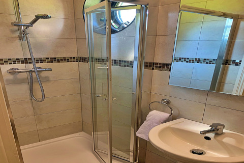 Salle de bain moderne dans un mobil-home à Oak Tree Lodge, Royaume-Uni, avec douche, lavabo et miroir.